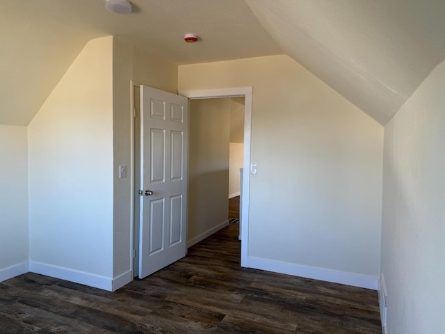 additional living space featuring baseboards, vaulted ceiling, and dark wood-style flooring