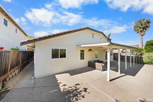 back of house with fence, outdoor lounge area, stucco siding, and a patio area