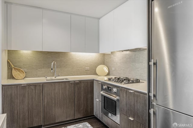 kitchen with tasteful backsplash, white cabinets, appliances with stainless steel finishes, light countertops, and a sink