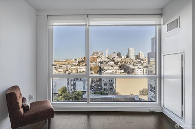 interior space featuring a wealth of natural light, a city view, visible vents, and wood finished floors