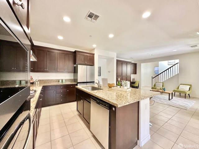 kitchen featuring light tile patterned floors, appliances with stainless steel finishes, a kitchen breakfast bar, a kitchen island with sink, and sink