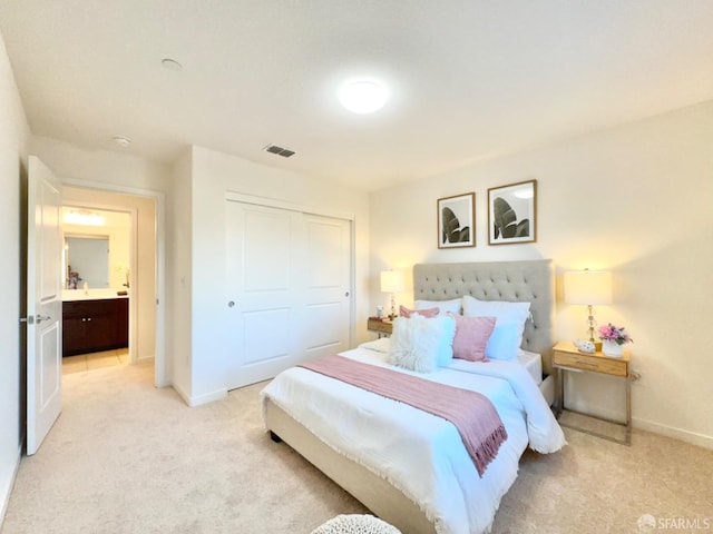 bedroom with connected bathroom, light colored carpet, and a closet