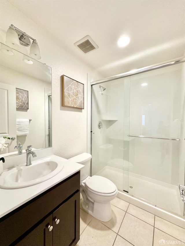 bathroom featuring vanity, tile patterned flooring, toilet, and an enclosed shower