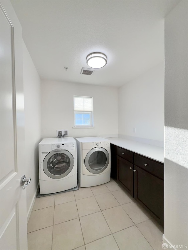 laundry area with cabinets, separate washer and dryer, and light tile patterned floors