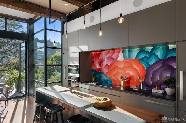 interior space featuring sink, hanging light fixtures, black stovetop, and a towering ceiling