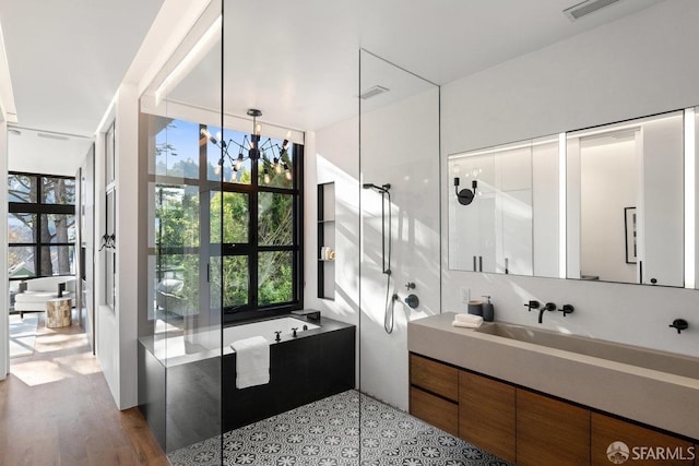 bathroom with hardwood / wood-style flooring, vanity, a notable chandelier, and separate shower and tub