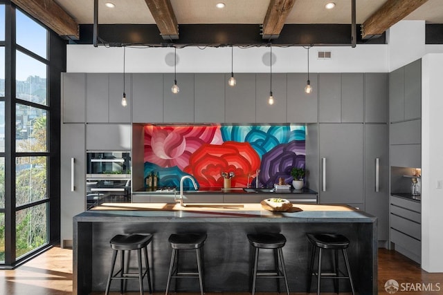 kitchen with a kitchen bar, beam ceiling, and a healthy amount of sunlight