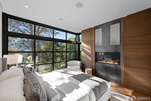 bedroom featuring expansive windows, wooden walls, and hardwood / wood-style flooring