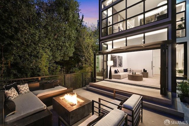 patio terrace at dusk featuring an outdoor living space with a fire pit