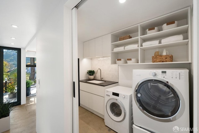 laundry area featuring cabinets, separate washer and dryer, and sink