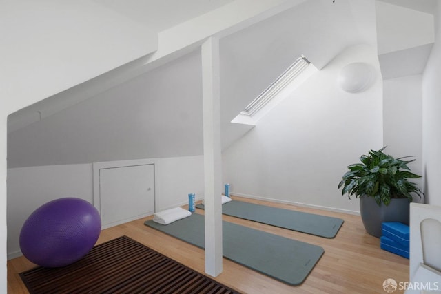 workout area with hardwood / wood-style flooring and lofted ceiling with skylight