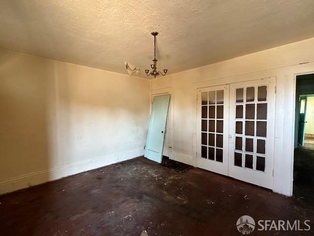 empty room with baseboards, a chandelier, concrete flooring, french doors, and a textured ceiling