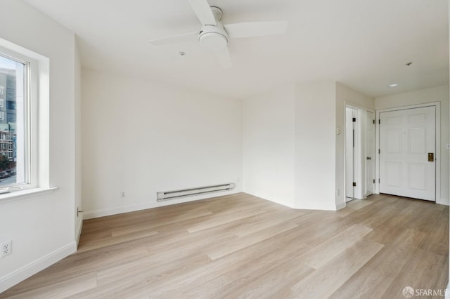 spare room with light hardwood / wood-style flooring, baseboard heating, and ceiling fan