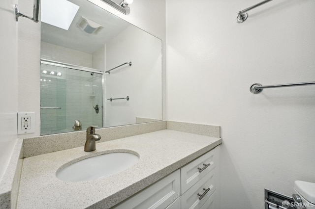 bathroom featuring vanity, toilet, and a shower with shower door