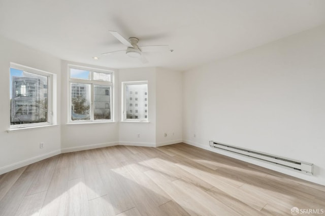 empty room featuring ceiling fan, baseboard heating, and light hardwood / wood-style flooring