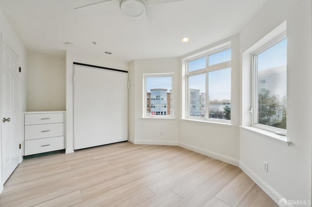 unfurnished bedroom featuring light wood-type flooring and multiple windows