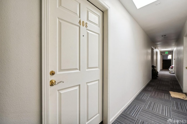 hallway featuring a skylight and dark carpet