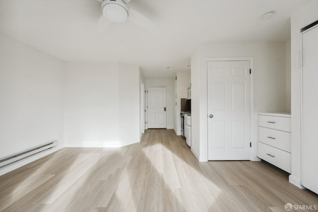 empty room featuring baseboard heating and light hardwood / wood-style floors