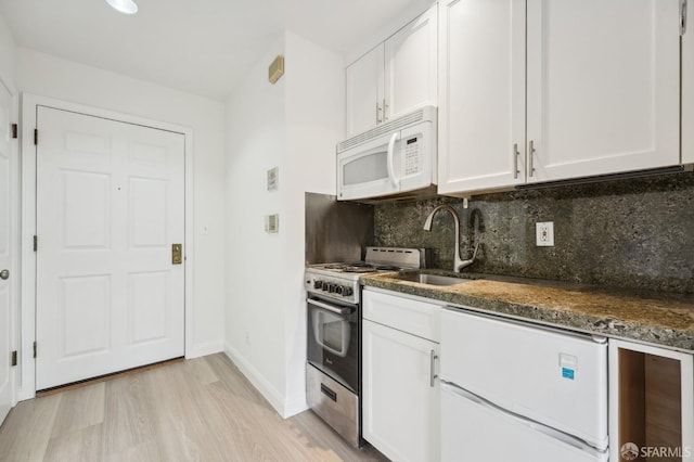 kitchen with stainless steel range, dark stone countertops, decorative backsplash, white cabinets, and light wood-type flooring