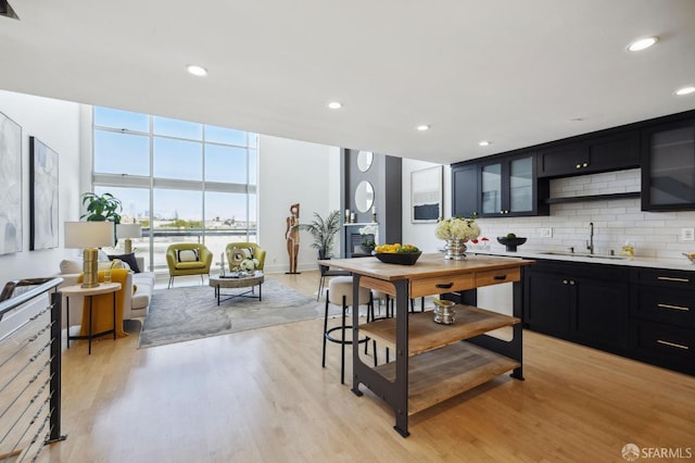 kitchen with tasteful backsplash, expansive windows, sink, and light hardwood / wood-style flooring