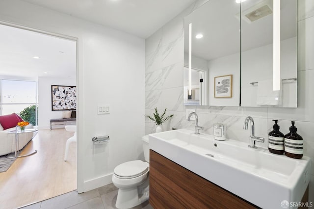 bathroom featuring tile patterned flooring, backsplash, tile walls, vanity, and toilet