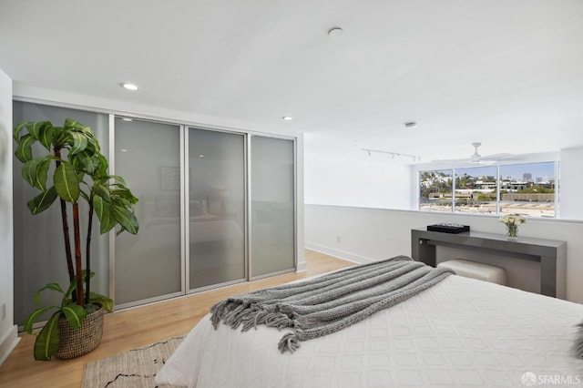 bedroom with track lighting, a closet, and light wood-type flooring