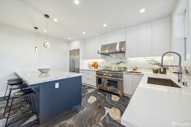 kitchen featuring sink, high end appliances, pendant lighting, range hood, and white cabinets