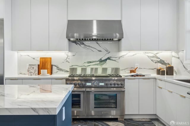 kitchen with white cabinetry, double oven range, backsplash, and exhaust hood