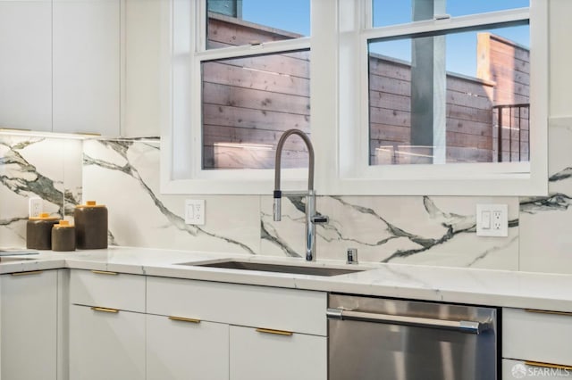 kitchen with white cabinetry, dishwasher, sink, and light stone counters