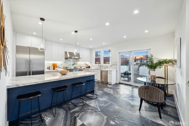 kitchen with white cabinetry, hanging light fixtures, light stone countertops, and appliances with stainless steel finishes