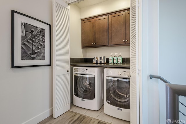 laundry area with light wood-type flooring, washing machine and dryer, cabinet space, and baseboards