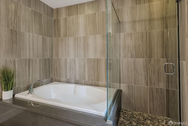 full bathroom featuring tile walls, a shower stall, and a bath