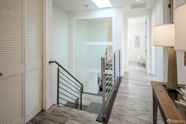 corridor with recessed lighting, visible vents, an upstairs landing, and wood finished floors