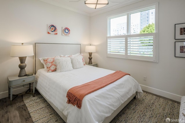 bedroom with crown molding, wood finished floors, and baseboards