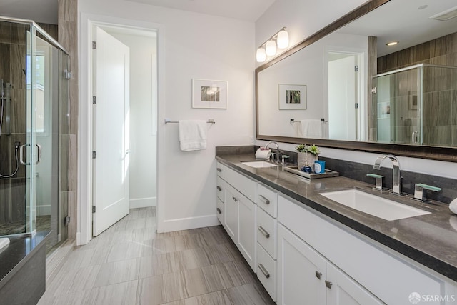 bathroom featuring a sink, a shower stall, and double vanity