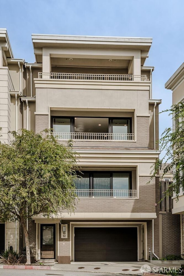 townhome / multi-family property featuring a garage, concrete driveway, brick siding, and stucco siding