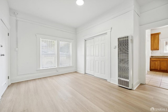 unfurnished bedroom with multiple windows, ensuite bath, light hardwood / wood-style floors, and a closet