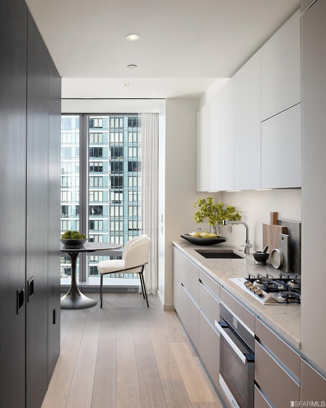 181 Fremont St Unit 54A, San Francisco, CA 94105 - kitchen featuring stainless steel appliances, modern cabinets, light wood-style floors, white cabinetry, and recessed lighting