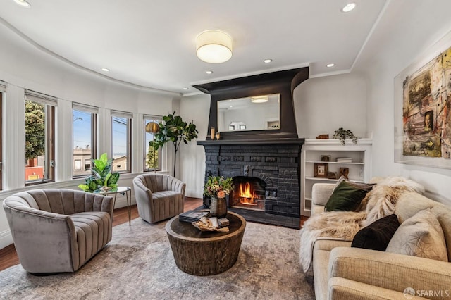 interior space with recessed lighting, a brick fireplace, crown molding, and wood finished floors