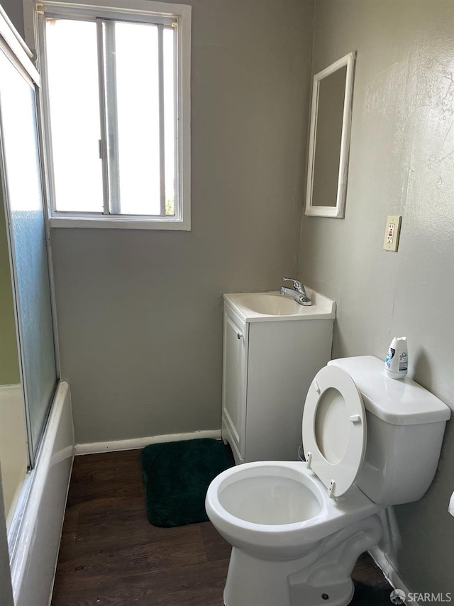 full bathroom featuring vanity, enclosed tub / shower combo, hardwood / wood-style flooring, and toilet