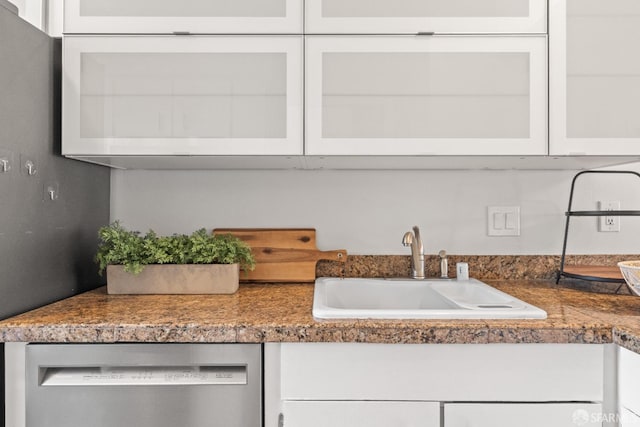 kitchen with dishwasher, a sink, white cabinetry, and glass insert cabinets