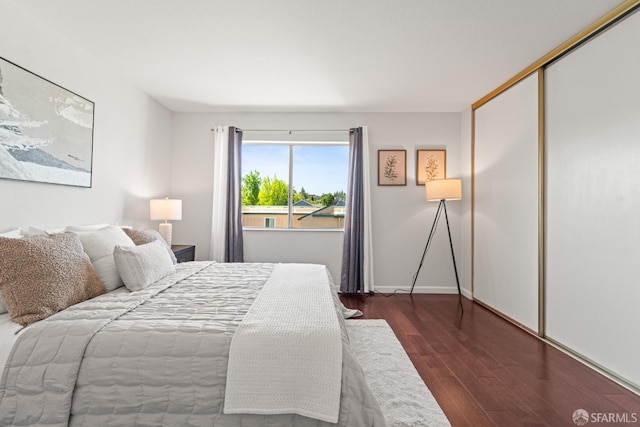 bedroom featuring dark wood-style floors, a closet, and baseboards