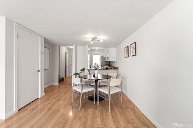 dining space featuring light wood-type flooring and baseboards