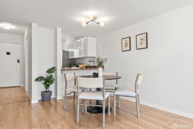 dining room featuring light wood-style flooring and baseboards