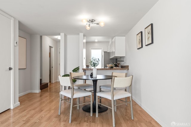 dining space featuring light wood-type flooring and baseboards