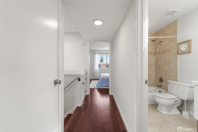 full bathroom with baseboards, toilet, bathing tub / shower combination, and wood finished floors
