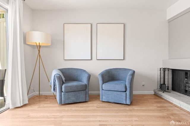 sitting room with light wood-style floors, a fireplace, and baseboards