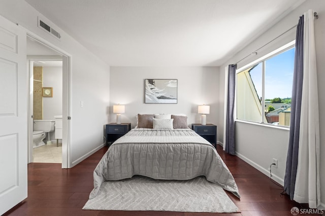 bedroom featuring wood finished floors, baseboards, and ensuite bathroom