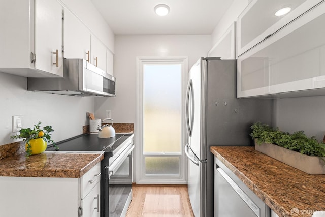 kitchen with appliances with stainless steel finishes, light wood-type flooring, white cabinetry, and dark countertops