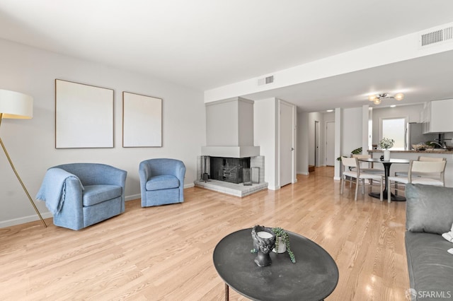living room with light wood-style floors, baseboards, and a fireplace